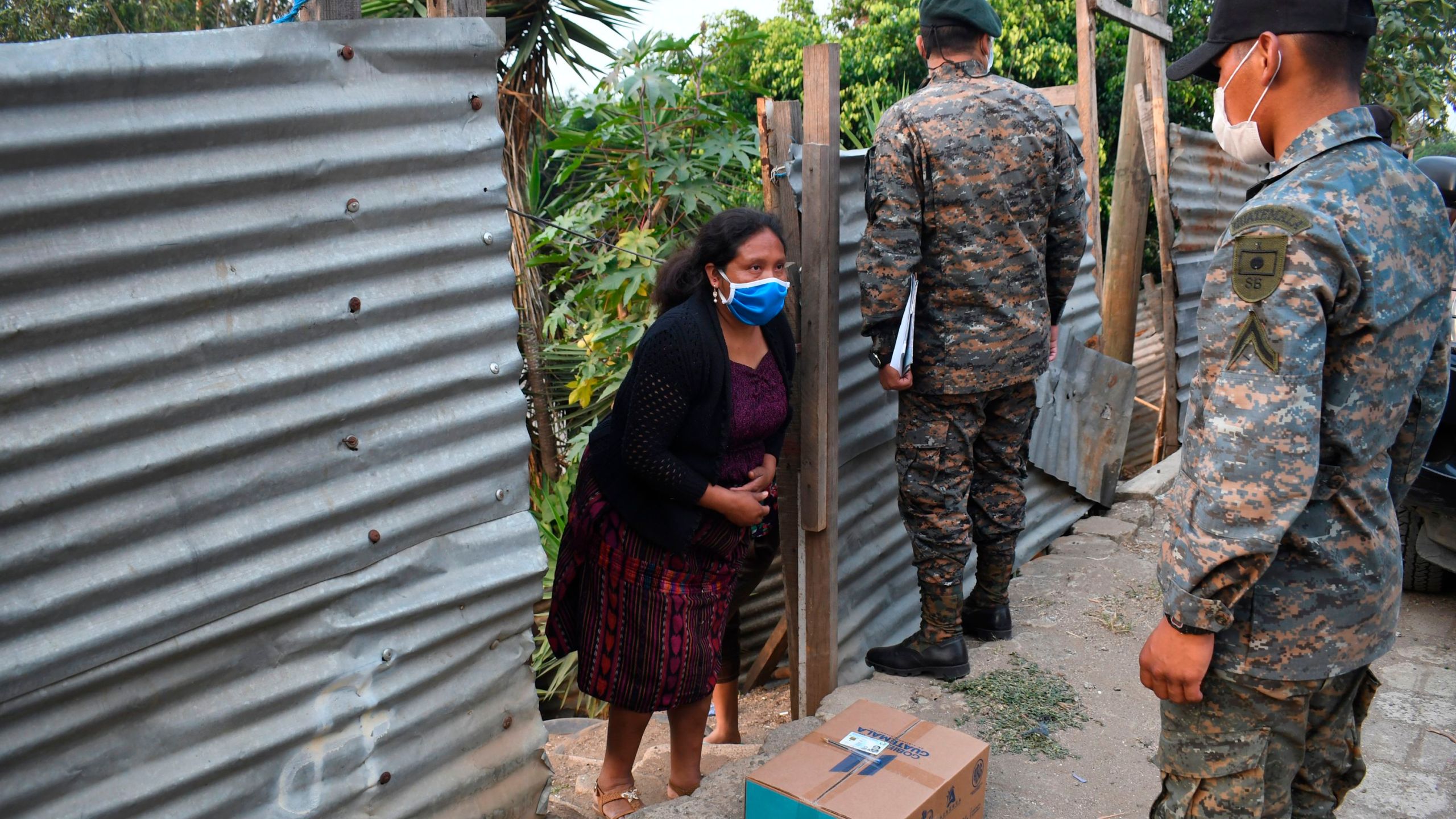 Guatemalan soldiers wearing face masks as a preventive measure against the spread of new coronavirus distribute boxes with food supplies at Las Brisas del Lago neighborhood during a partial curfew ordered by the government in Guatemala. (JOHAN ORDONEZ/AFP via Getty Images)