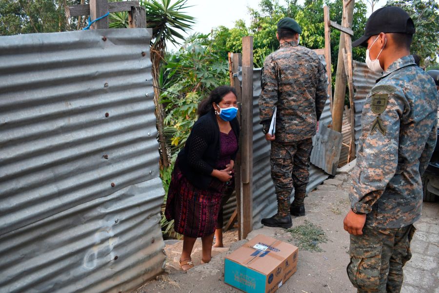 Guatemalan soldiers wearing face masks as a preventive measure against the spread of new coronavirus distribute boxes with food supplies at Las Brisas del Lago neighborhood during a partial curfew ordered by the government in Guatemala. (JOHAN ORDONEZ/AFP via Getty Images)