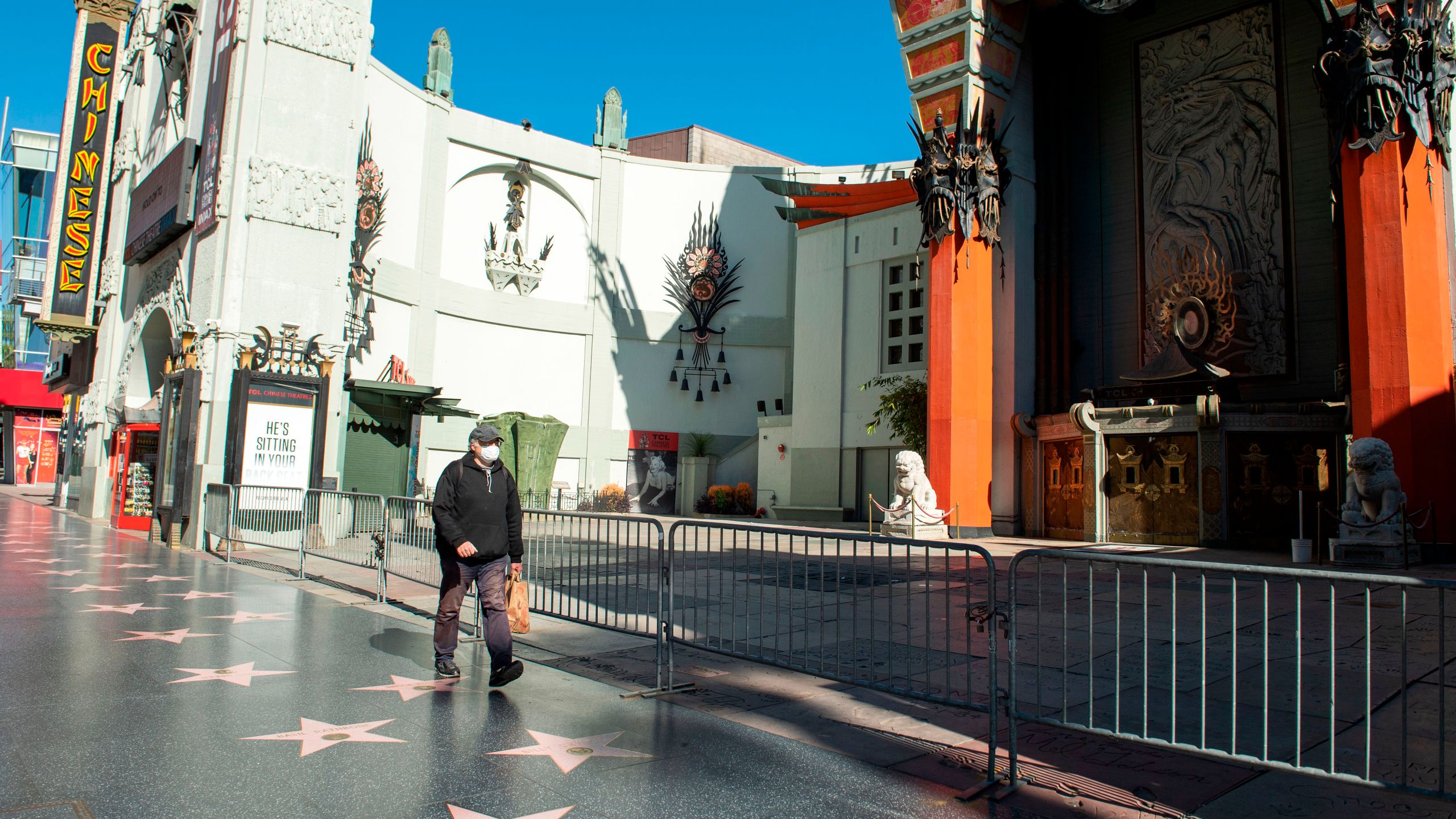 A person wearing a mask walks past the TCL Chinese Theater during the COVID-19 crisis on April 15, 2020, in Hollywood, California. (VALERIE MACON/AFP via Getty Images)