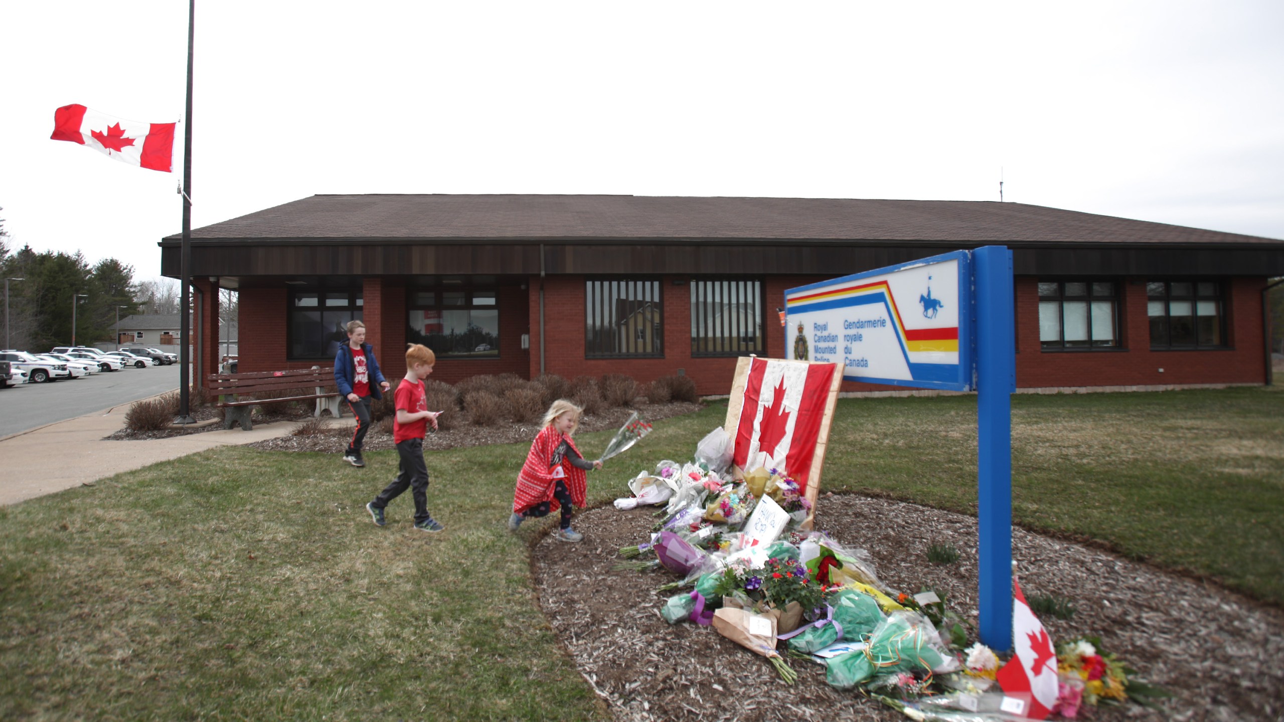 Children lay flowers at an impromptu memorial in front of the RCMP detachment April 20, 2020, in Enfield, Nova Scotia, Canada. It was the home detachment of slain RCMP Constable Heidi Stevenson, who was one of 19 people killed during a shooting rampage in April 2020. (Tim Krochak/Getty Images)