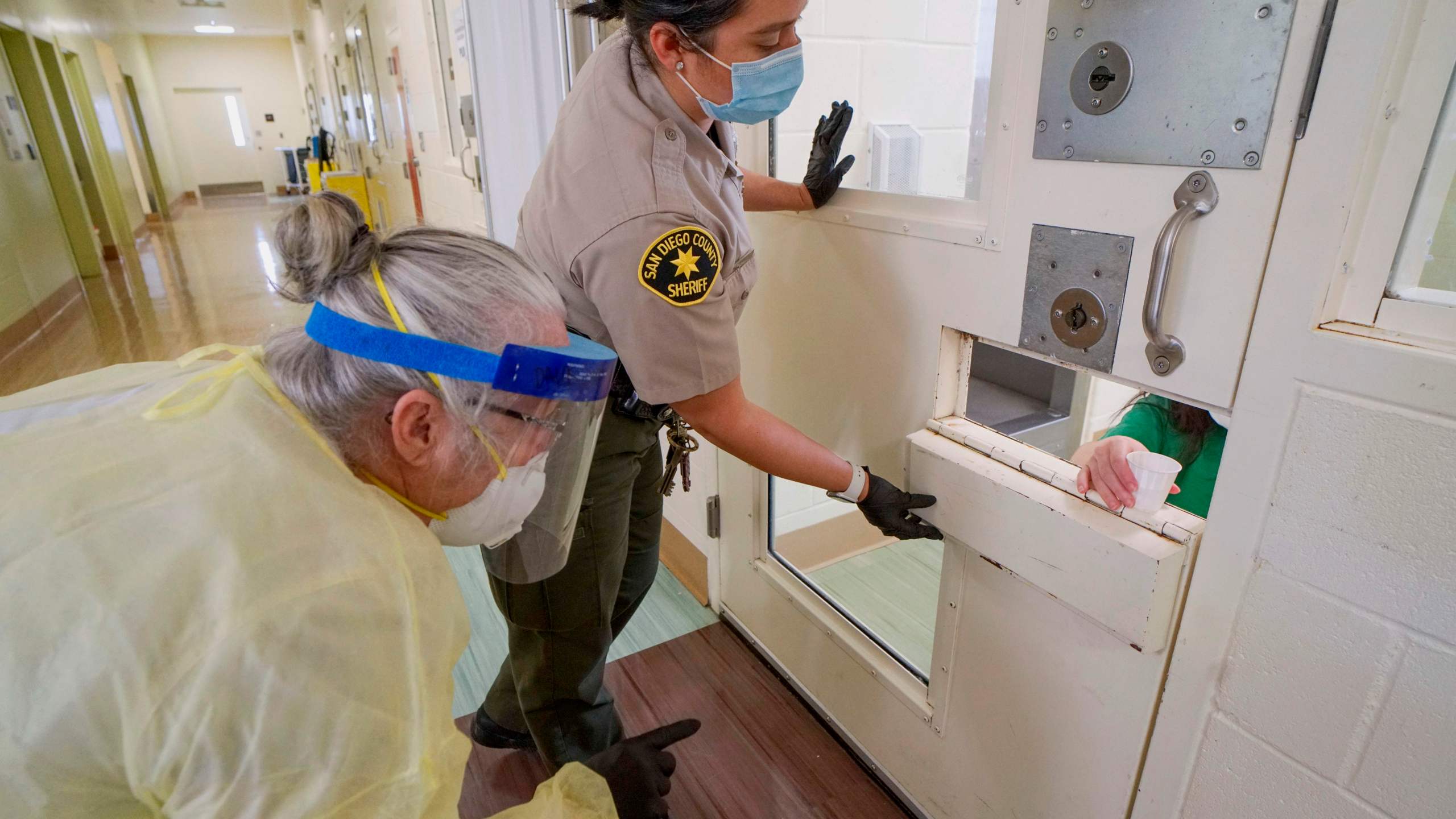 A Sheriff's deputy and an on-site nurse give medications to an inmate at Las Colinas Women's Detention Facility in Santee, California, on April 22, 2020. (Sandy Huffaker/ AFP via Getty Images)