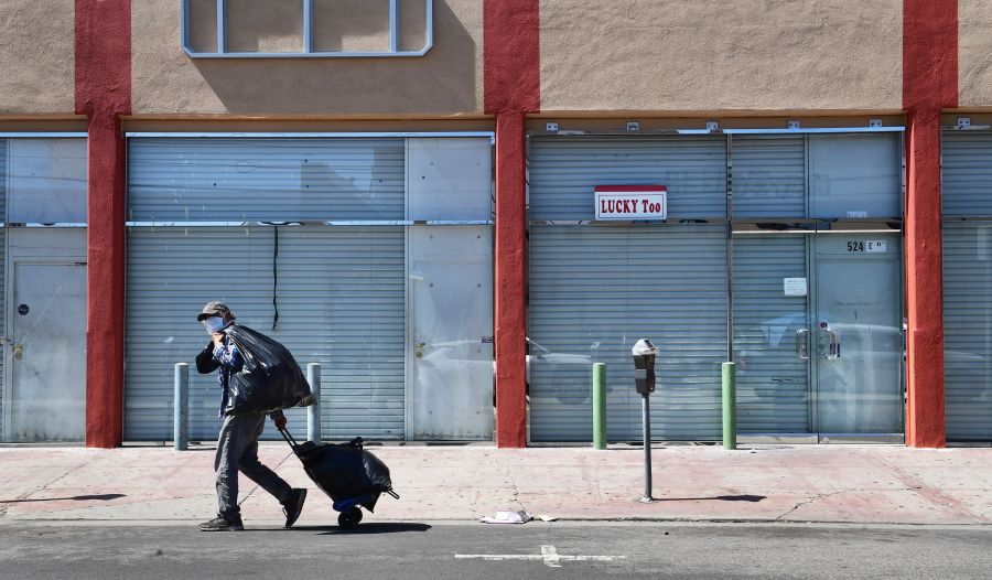 A man in a face mask walks past closed shopfronts in the Fashion District in Downtown Los Angeles, California on April 22, 2020, amid the novel coronavirus pandemic. More than 50% of Angelenos are now unemployed, according to a national survey. (FREDERIC J. BROWN/AFP via Getty Images)