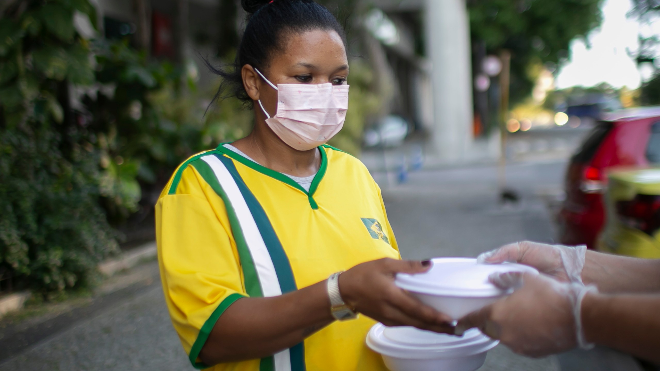 A homeless and unemployed person receives food and water from volunteers of the 'Covid Sem Fome' on April 22, 2020 in Rio de Janeiro, Brazil. (Bruna Prado/Getty Images)