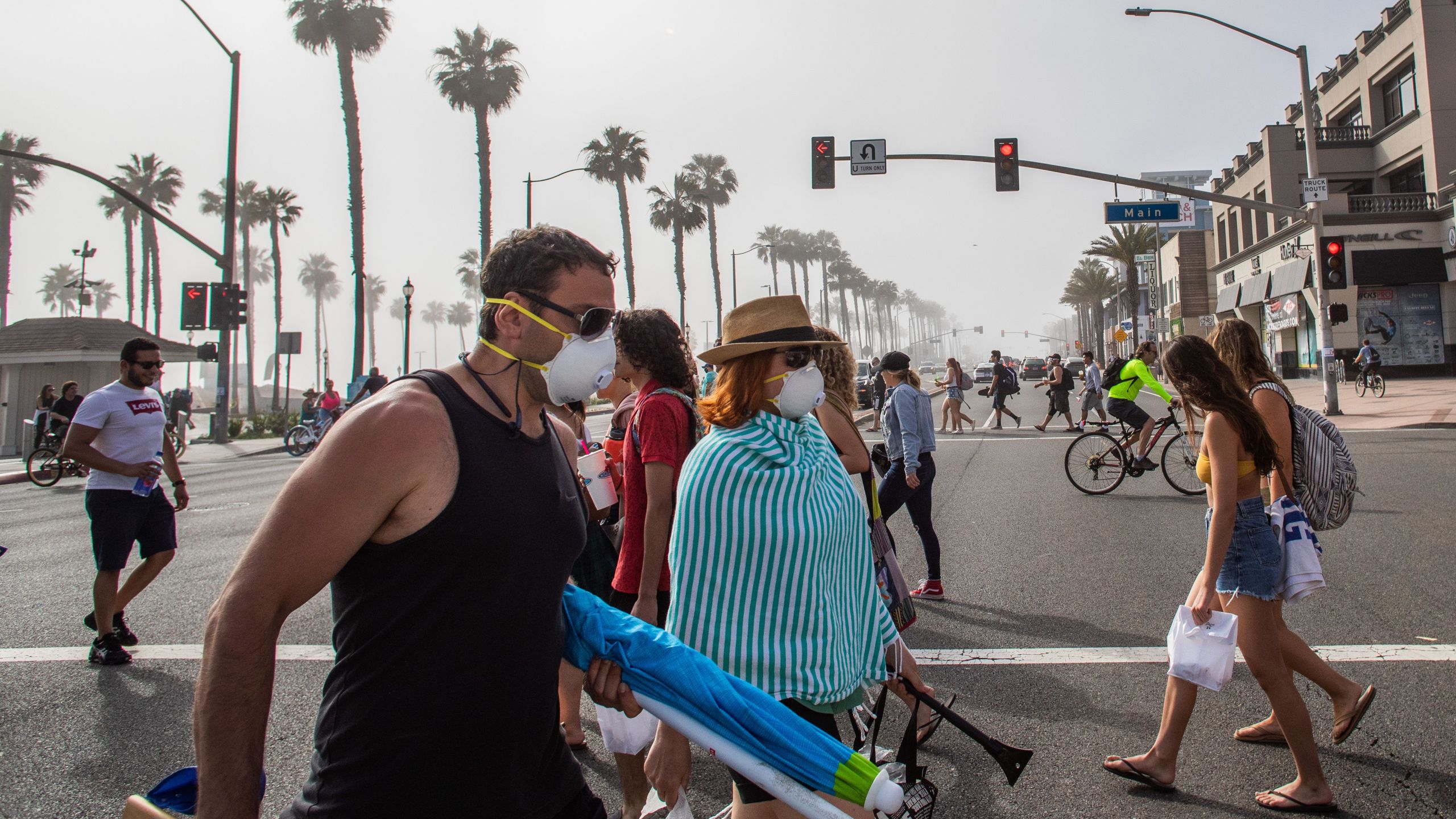 People cross the street, some wearing masks, in Huntington Beach amid the novel coronavirus pandemic on April 25, 2020. (Apu Gomes / AFP / Getty Images)