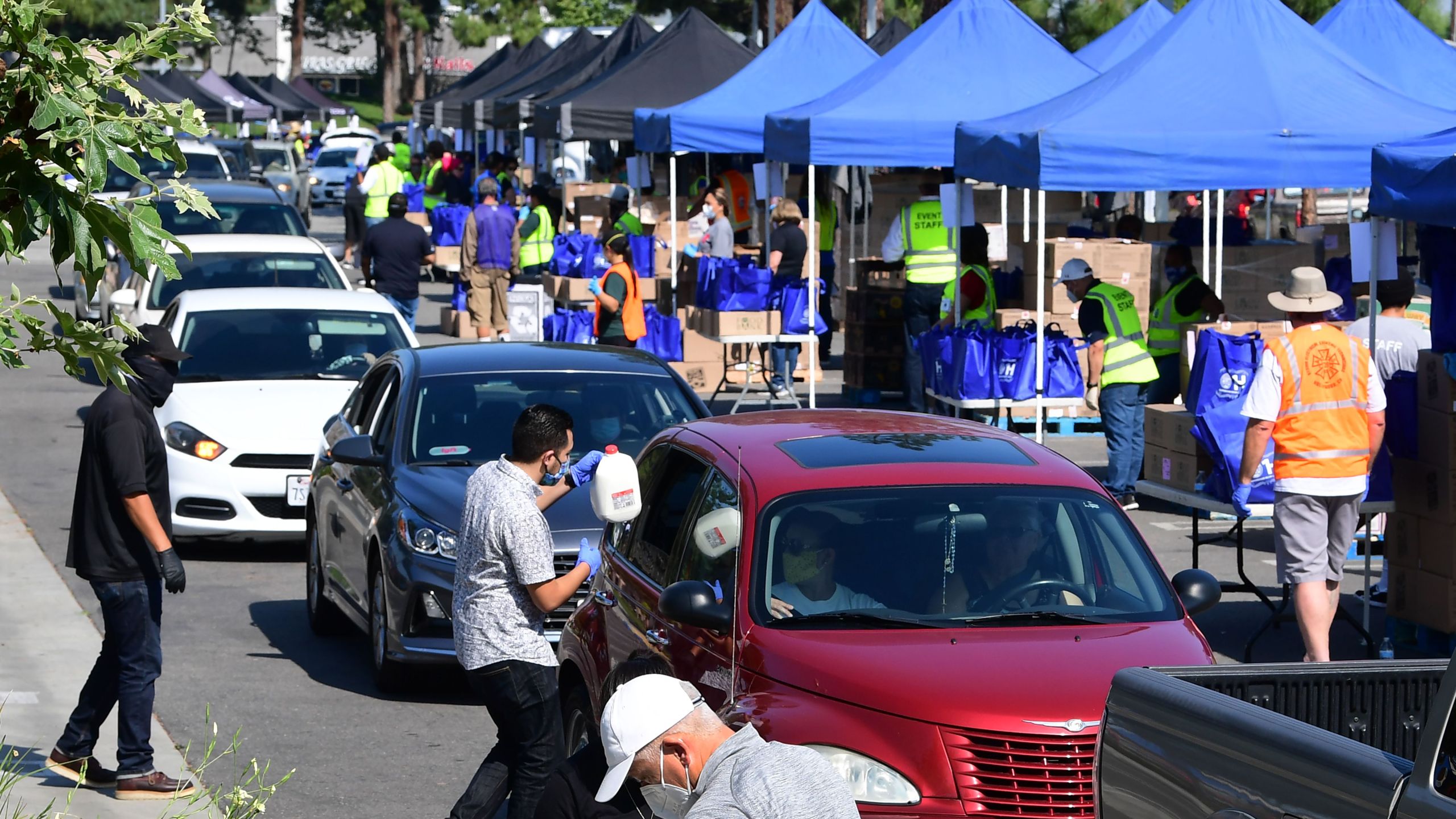 Volunteers help load food as vehicles arrive at a Los Angeles Regional Food Bank drive-thru giveaway in Pico Rivera on April 28, 2020. (FREDERIC J. BROWN/AFP via Getty Images)