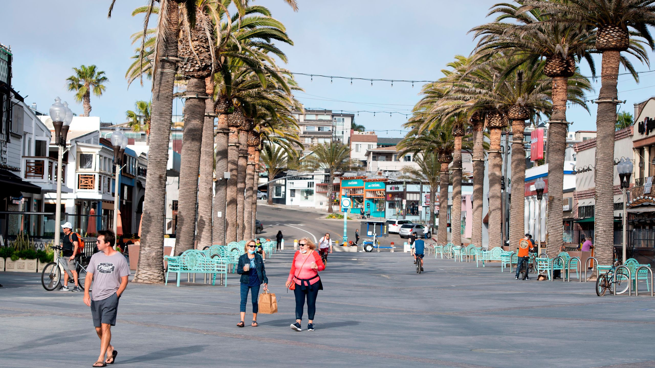 People walk around the entrance of the Hermosa Beach pier during the novel coronavirus pandemic on April 28, 2020. (Credit: Valerie Macon / AFP / Getty Images)