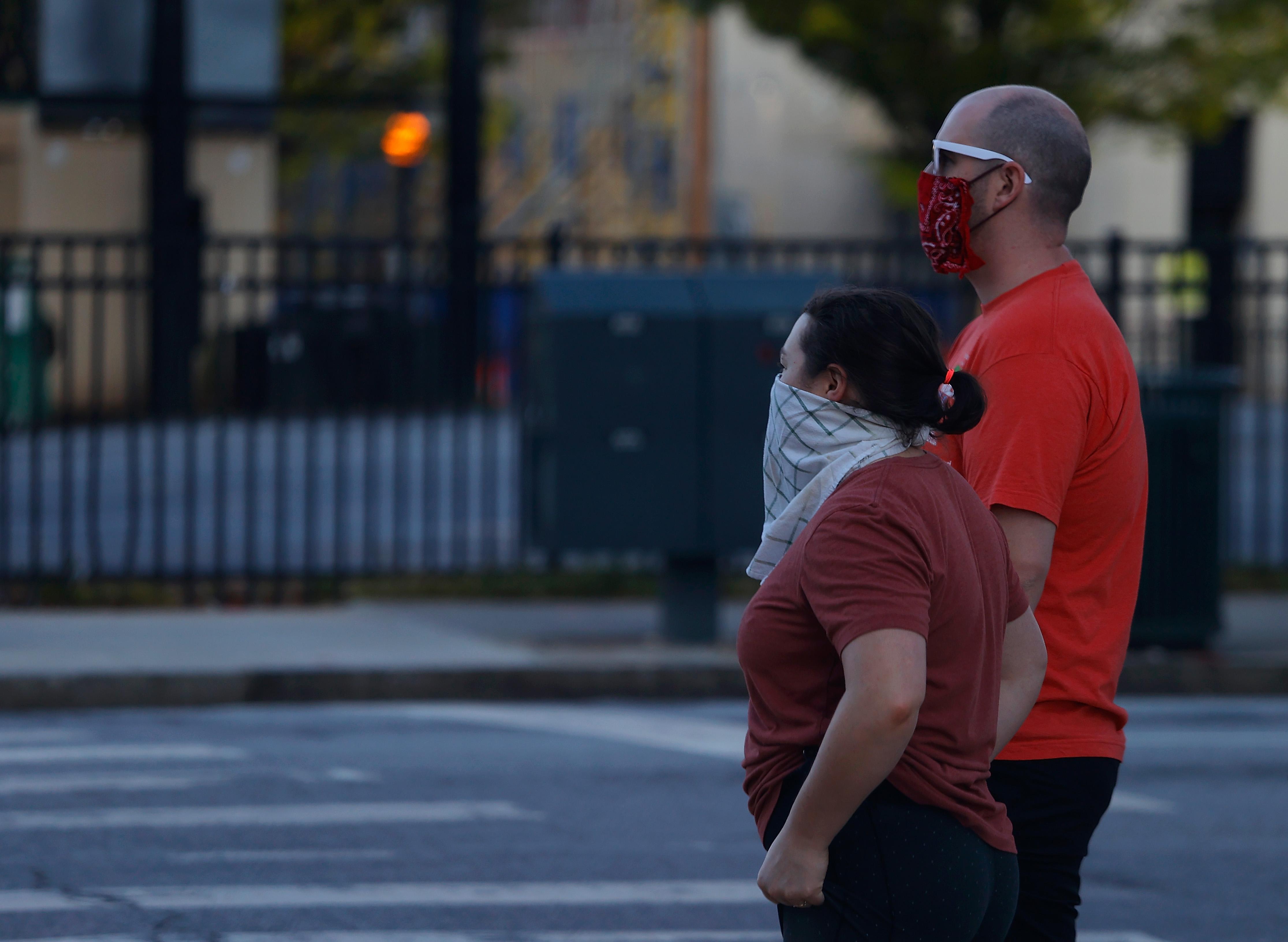 Two pedestrians wearing bandanas over their faces wait to cross Centennial Olympic Park Drive NW on April 4, 2020 in Atlanta, Georgia. (Kevin C. Cox/Getty Images)