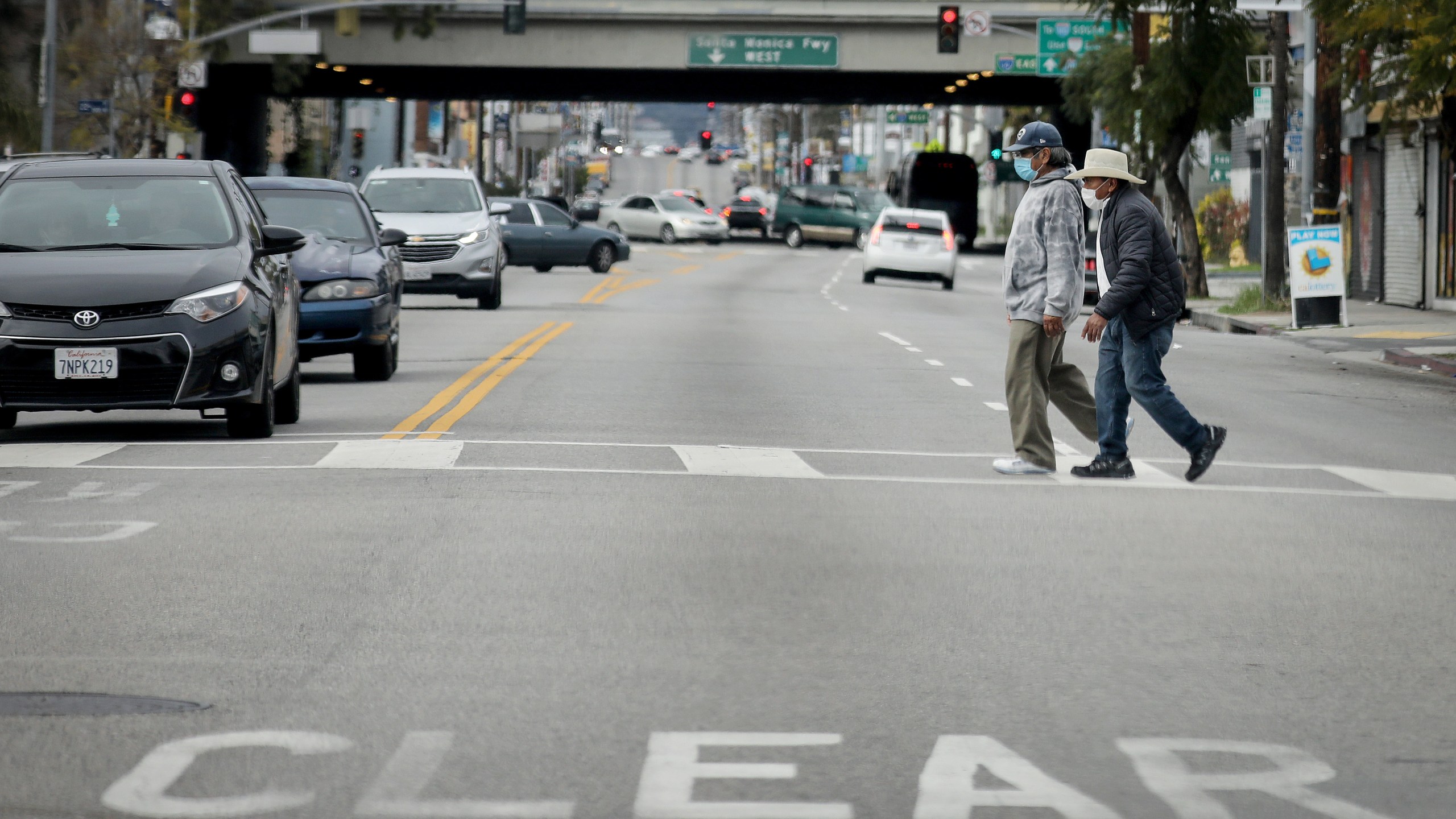 Men cross a street wearing face masks amid the coronavirus pandemic in Los Angeles on April 6, 2020. (Mario Tama/Getty Images)