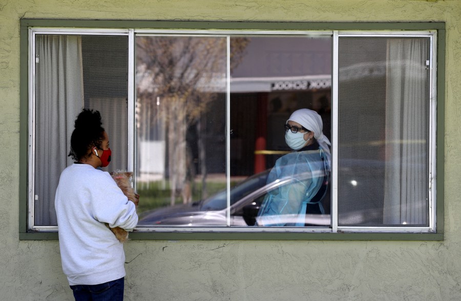 A woman talks with a nurse through a window as she visits her father who is a patient at a nursing home with a cluster of COVID-19 cases in Hayward, California, on April 14, 2020. (Justin Sullivan/Getty Images)