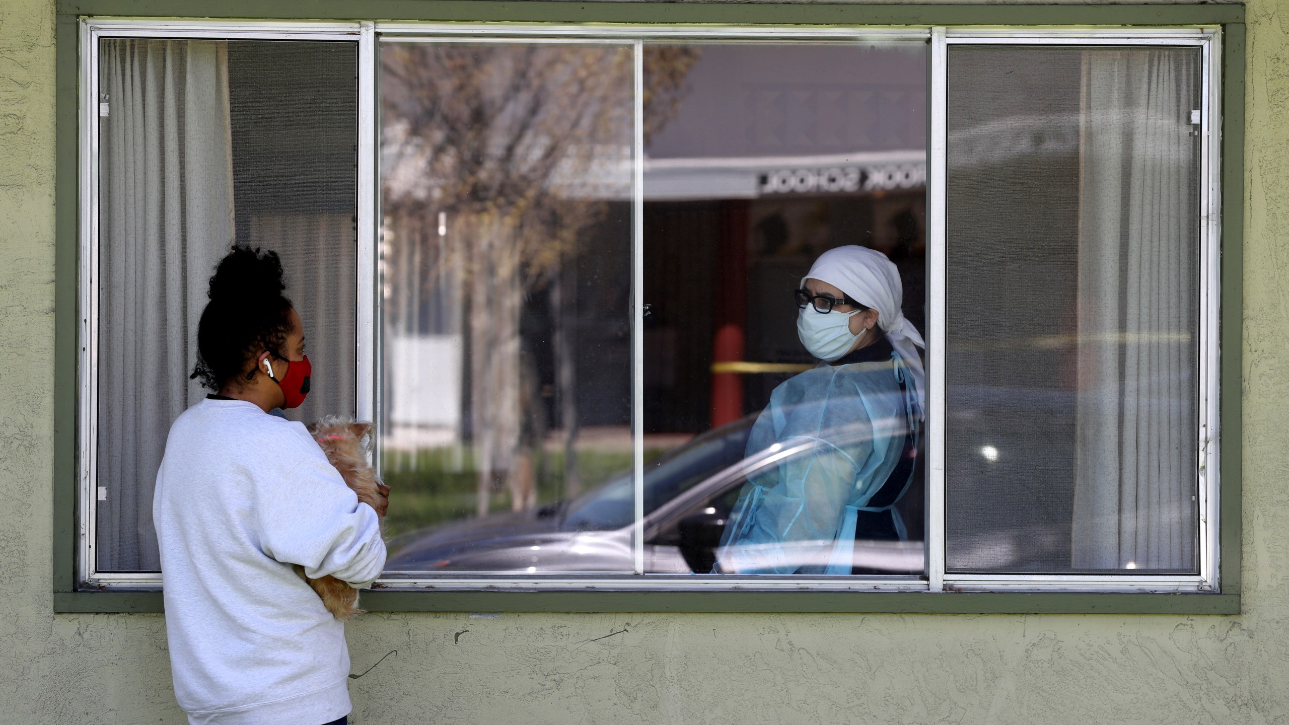 Adrina Rodriguez (L) talks with a nurse through a window as she visits her father who is a patient at the Gateway Care and Rehabilitation Center that has tested negative for COVID-19 on April 14, 2020, in Hayward, California. (Justin Sullivan/Getty Images)