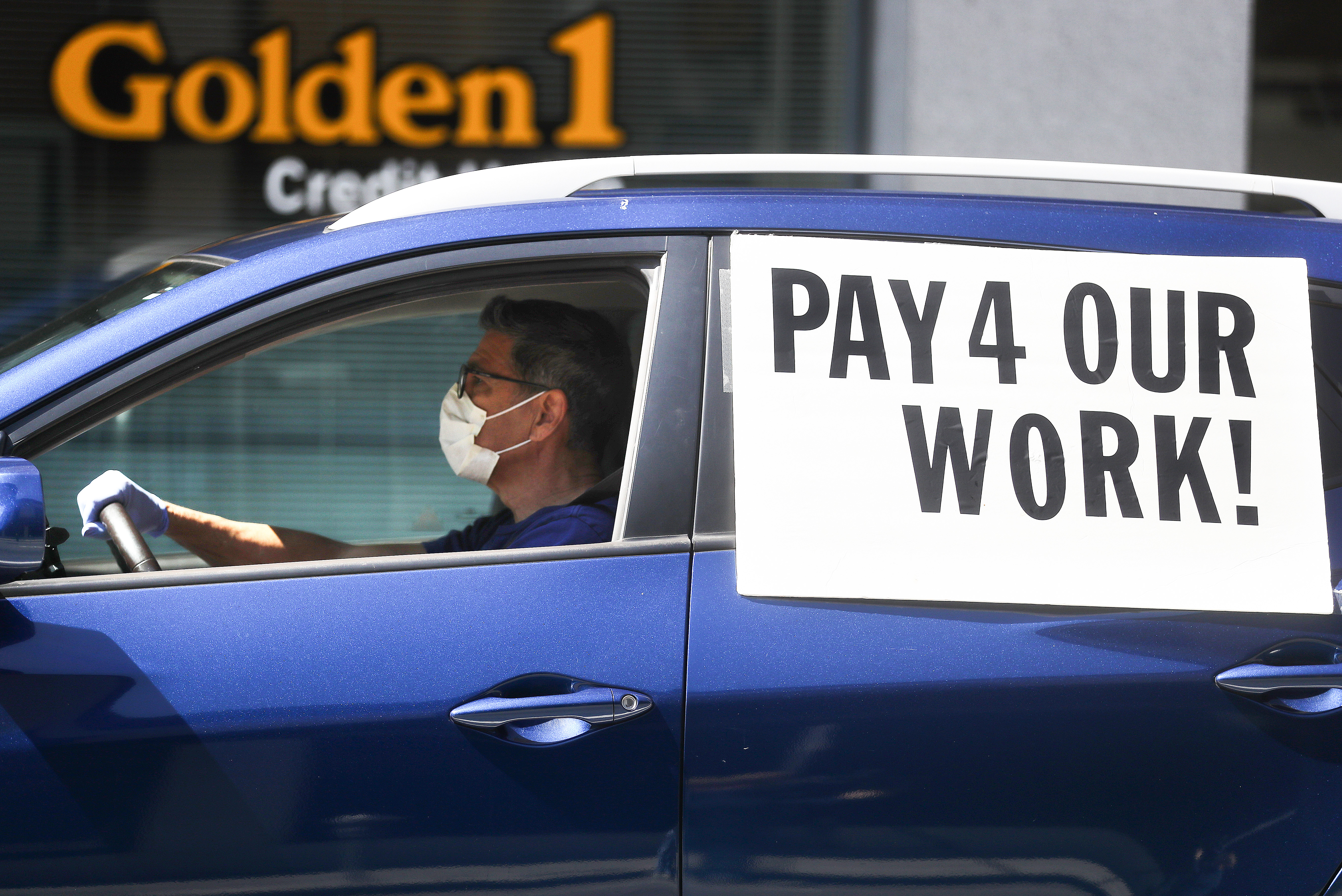 A driver wears a face mask and gloves as Uber and Lyft drivers with Rideshare Drivers United and the  Transport Workers Union of America conduct a" "caravan protest" outside the California Labor Commissioner’s office amidst the coronavirus pandemic on April 16, 2020 in Los Angeles. (Mario Tama/Getty Images)