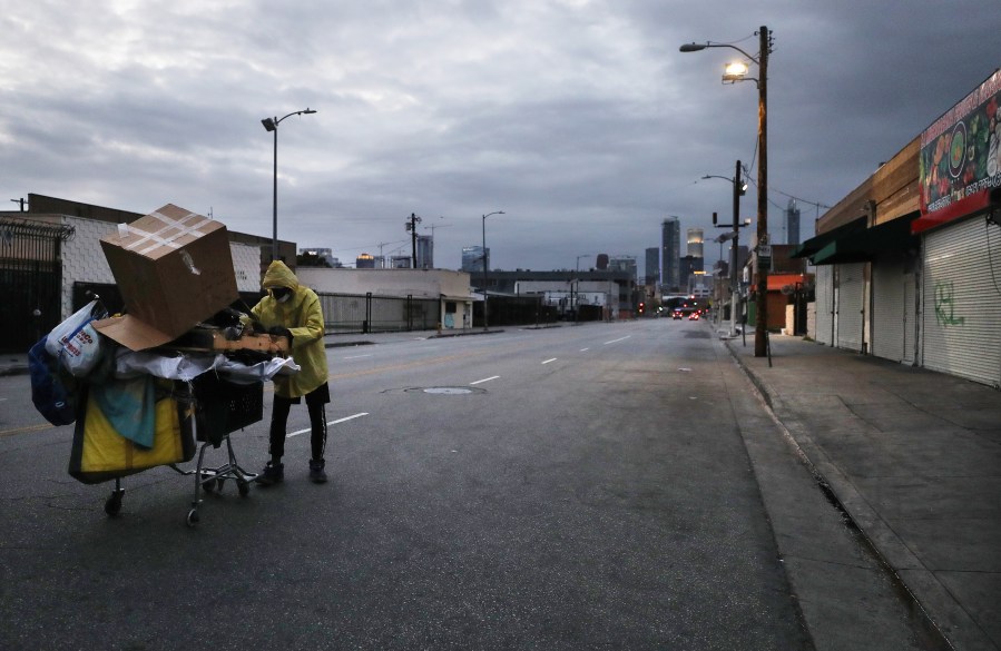 A man who is originally from Texas and currently homeless pushes a cart with his belongings on a downtown Los Angeles street amidst the coronavirus pandemic on April 18, 2020. (Credit: Mario Tama / Getty Images)