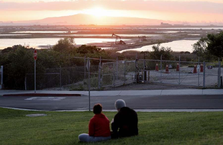 People sit on a hillside overlooking oil pumpjacks at the Huntington Beach Oil Fields amidst the coronavirus pandemic on April 20, 2020 in Huntington Beach, California. (Mario Tama/Getty Images)