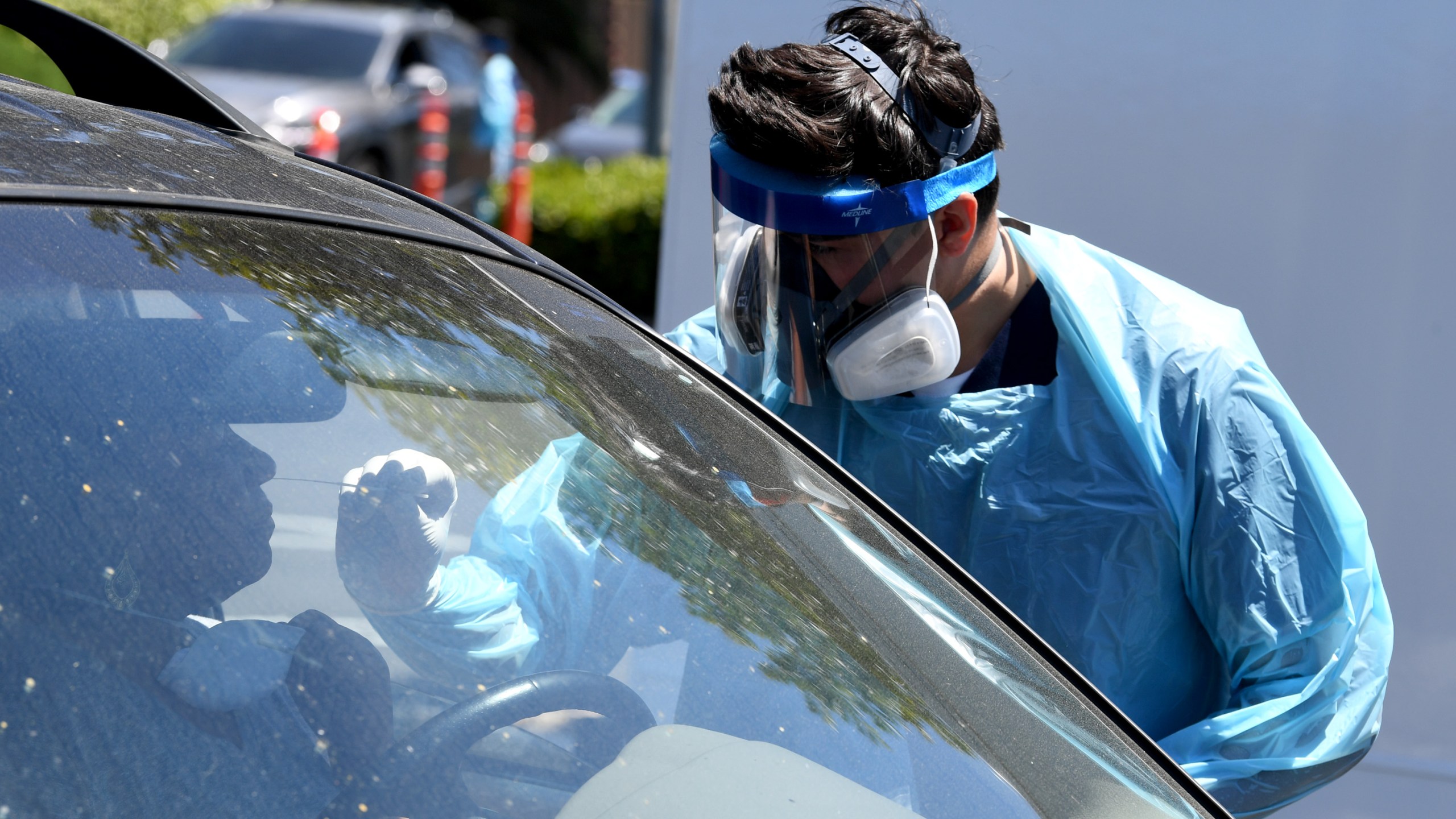 Workers wearing personal protective equipment perform drive-up COVID-19 testing at Mend Urgent Care testing site for the novel coronavirus at the Westfield Culver City on April 24, 2020, in Culver City. A nasopharyngeal swab test kit is used at this COVID-19 testing center to determine the viral load and virus count of a patient. (Kevin Winter / Getty Images)