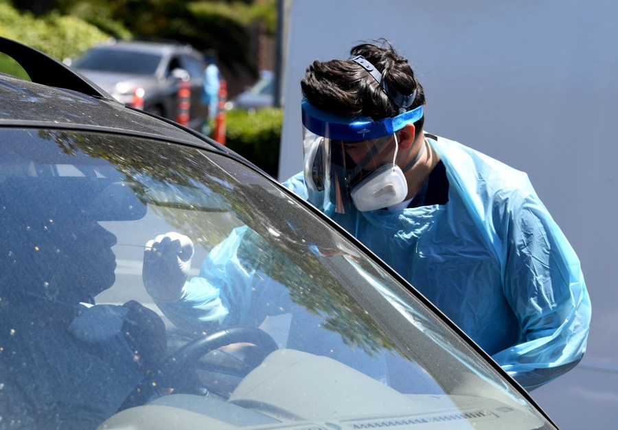 Workers wearing personal protective equipment perform drive-up COVID-19 testing at Mend Urgent Care testing site for the novel coronavirus at the Westfield Culver City on April 24, 2020, in Culver City. A nasopharyngeal swab test kit is used at this COVID-19 testing center to determine the viral load and virus count of a patient. (Kevin Winter / Getty Images)