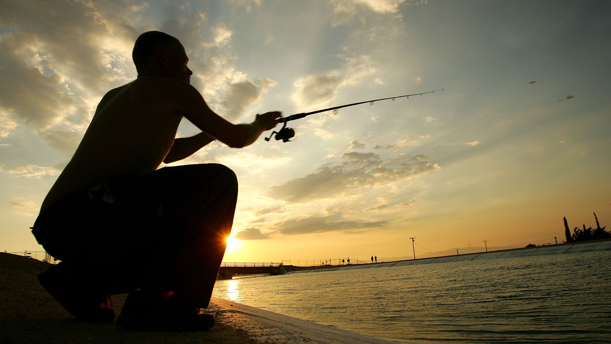 Tyrone Burchett casts his fishing line into the California Aqueduct, which carries water hundreds of miles from northern California to the state's southern cities, near his home at sunset on July 27, 2005, in Palmdale, California. (David McNew/Getty Images)