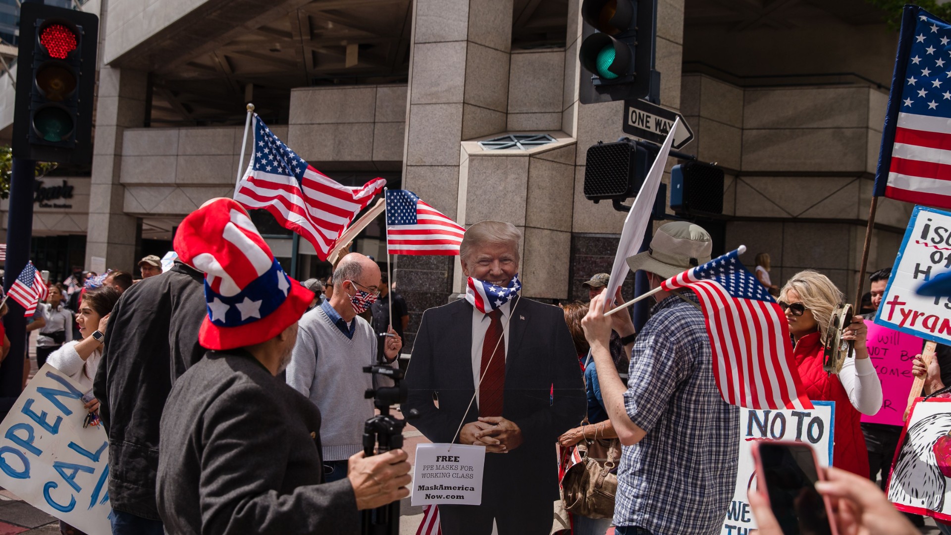 A Trump cutout with a US flag around its neck is seen next to protesters rallying in downtown San Diego against California's stay at home order to prevent the spread of the novel coronavirus, which causes COVID-19, on April 18, 2020. (Ariana Drehsler/AFP/Getty Images)