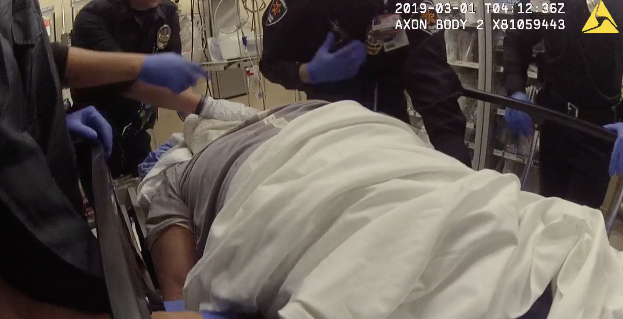 An LAPD officer places his hand on the face of a man in custody while being treated at a hospital in downtown L.A. on Feb. 28, 2019. This is a still from an officer's body cam footage, which was obtained by the man's legal team before he sued the department on April 1, 2020. (Matthew Strugar)