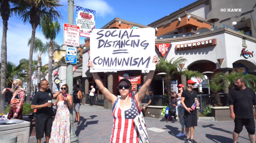 A protestor holds up a sign during a rally in Huntington Beach on April 17, 2020. (OC Hawk)