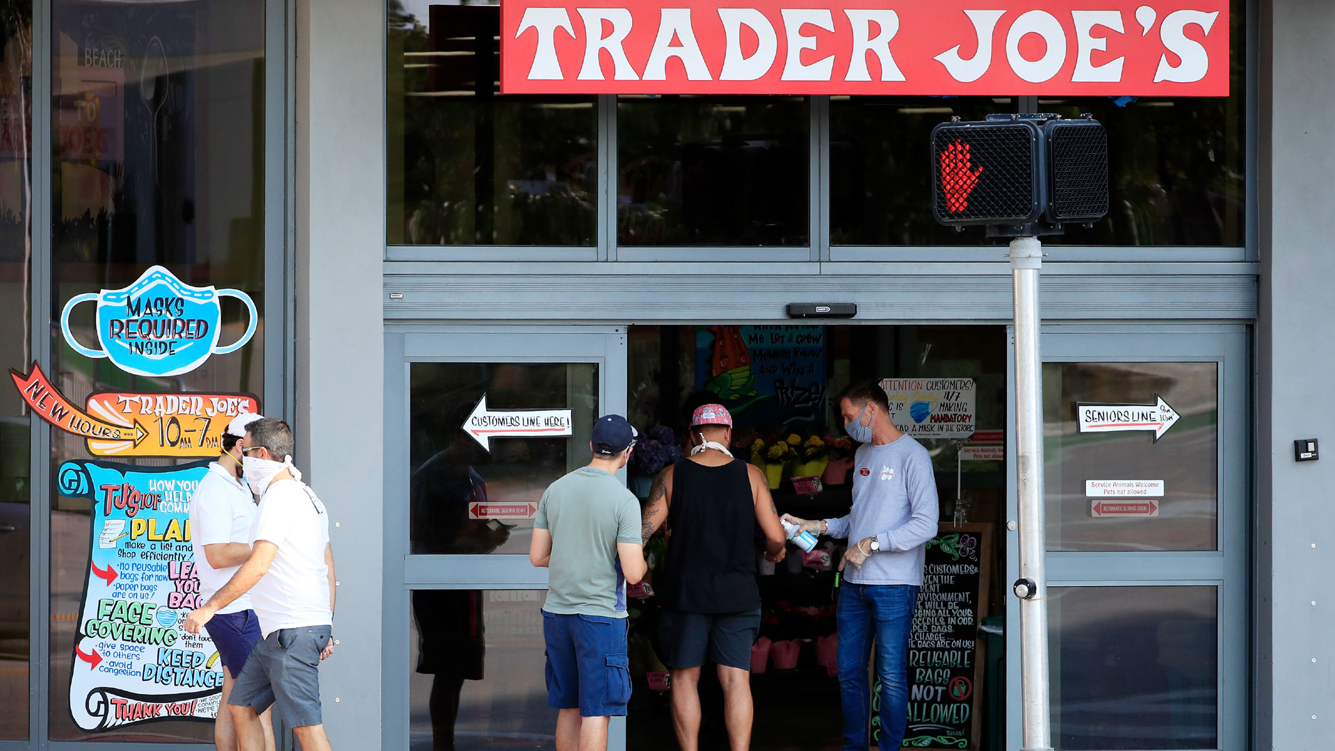 A store associate distributes hand sanitizer to customers as they enter the Trader Joe's store in South Beach on April 14, 2020, in Miami Beach, Florida. (Cliff Hawkins/Getty Images)