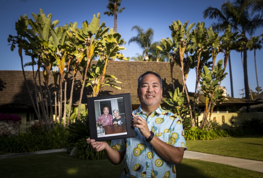 Mason Nakamura holds a photo of himself with his late mother, Mary Nakamura, at his home in Santa Ana. (Allen J. Schaben / Los Angeles Times)