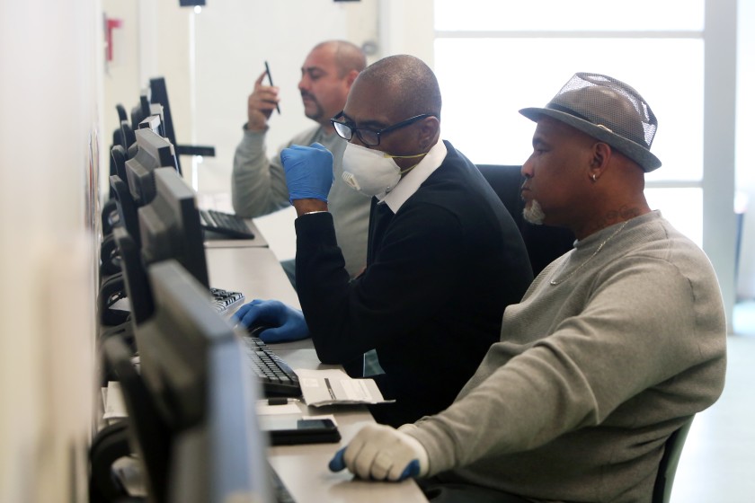 Stanley Smith, center, with South L.A. WorkSource Center helps Gregory Allen, right, with a job search.(Dania Maxwell/Los Angeles Times)