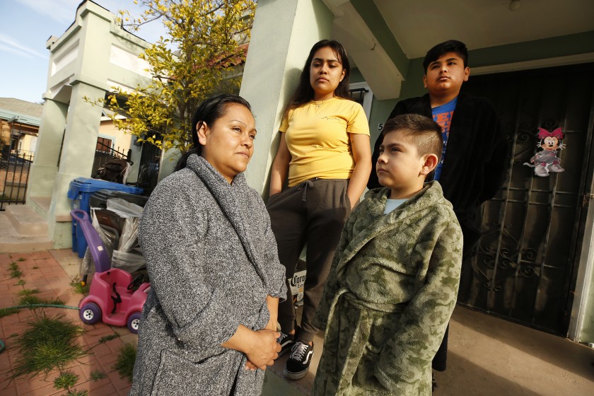 Raquel Lezama, left, outside her home in Los Angeles after walking with her daughter Monica Ramos, center, to Manual Arts High School to pick up grab-and-go meals for the family.(Al Seib/Los Angeles Times)