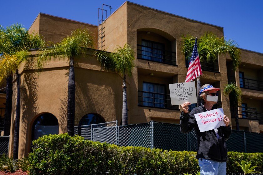 Protester Karen Litfin of Laguna Hills stands outside the Laguna Hills Inn, which the county is planning to use to house homeless people with the coronavirus, in this undated photo. (Credit: Kent Nishimura / Los Angeles Times)