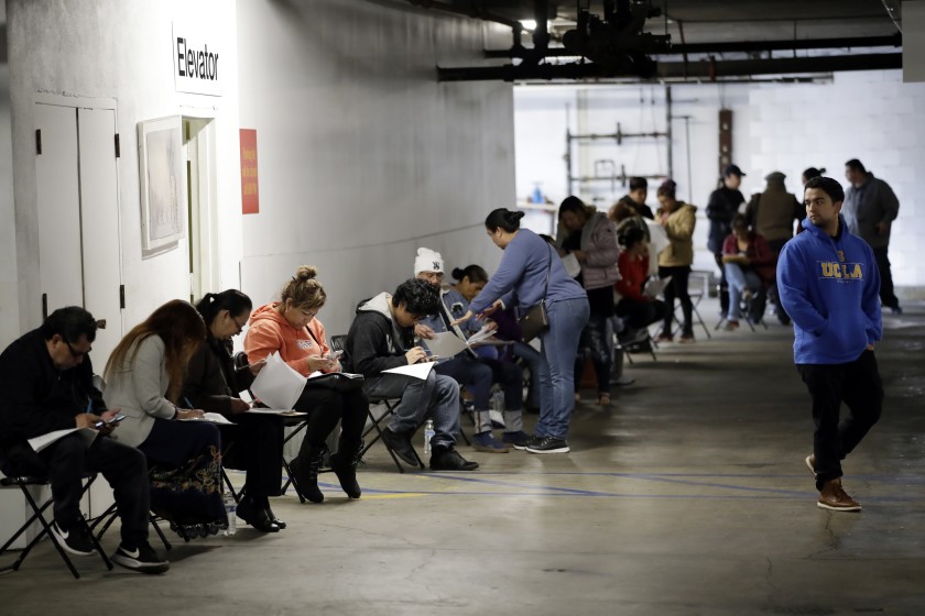 Unionized hospitality workers wait in line in a basement garage to apply for unemployment benefits at the Hospitality Training Academy on March 13 in Los Angeles. (Luis Sinco / Los Angeles Times)