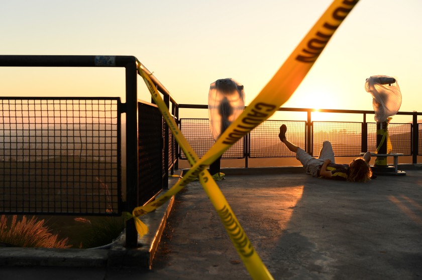 A man relaxes next to caution tape at Griffith Observatory as Los Angeles remains locked down because of the coronavirus on April 28, 2020. (Wally Skalij / Los Angeles Times)