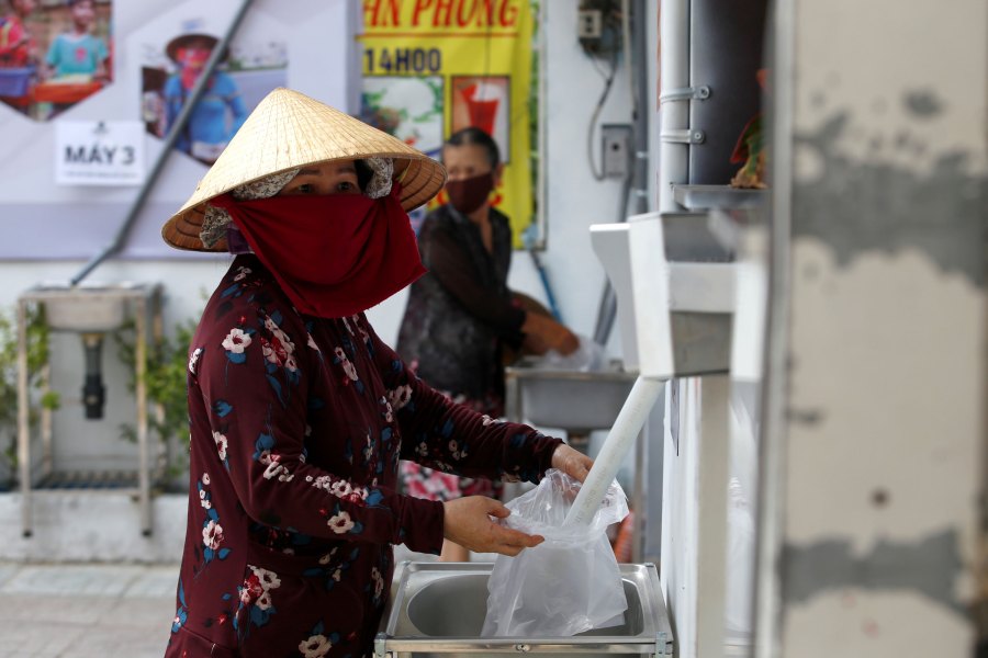 A woman fills a plastic bag with rice from a 24/7 automatic rice dispensing machine in Ho Chi Minh City, Vietnam, on April 11, 2020. (Yen Duong/Reuters)