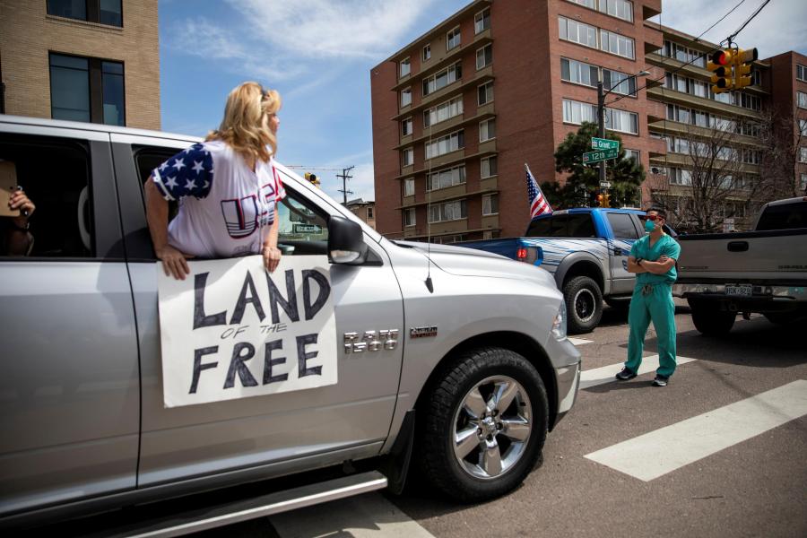 A health care worker stands in the street in counterprotest to the hundreds of people demanding the stay-at-home order be lifted in Denver, Colorado on April 19, 2020. (Alyson McClaran/Reuters)