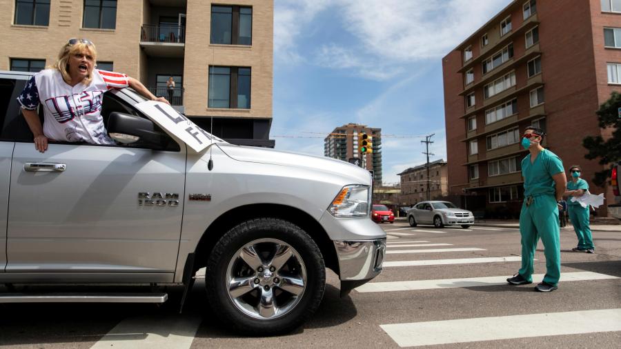 A health care worker stands in the street in counterprotest to the hundreds of people demanding the stay-at-home order be lifted in Denver, Colorado on April 19, 2020. (Alyson McClaran/Reuters)