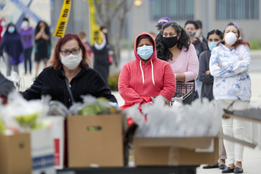 People wait in line Friday to get meal packs provided by the Los Angeles Unified School District at the “grab-and-go” food center in front of Byrd Middle School in Sun Valley, part of the district’s exploding costs related to the COVID-19 pandemic.(Irfan Khan / Los Angeles Times)