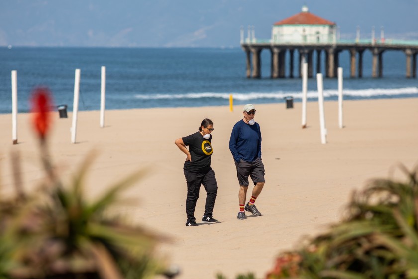 Above, two people on the sand at Manhattan Beach in late March 2020 despite beach closures. (Jay L. Clendenin/ Los Angeles Times)