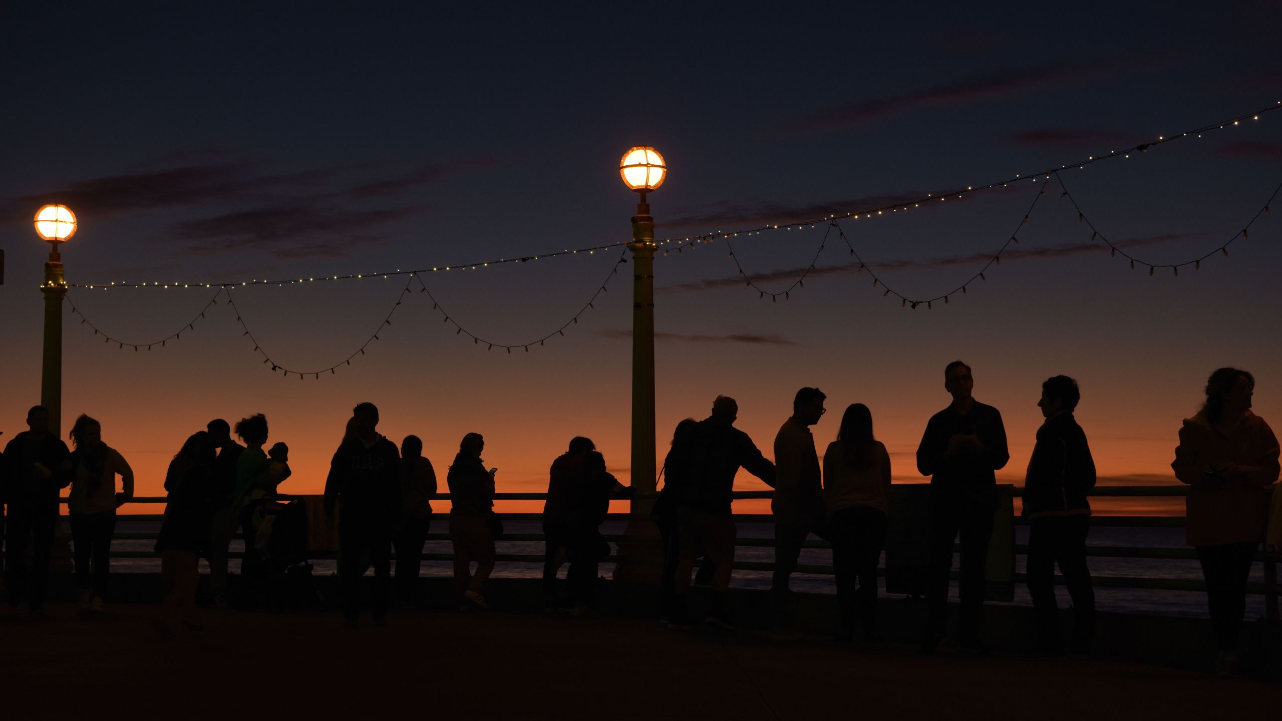 People enjoy the last sunset of the year on the pier in Manhattan Beach on Dec. 31, 2019. (Credit: Agustin Paullier / AFP / Getty Images)