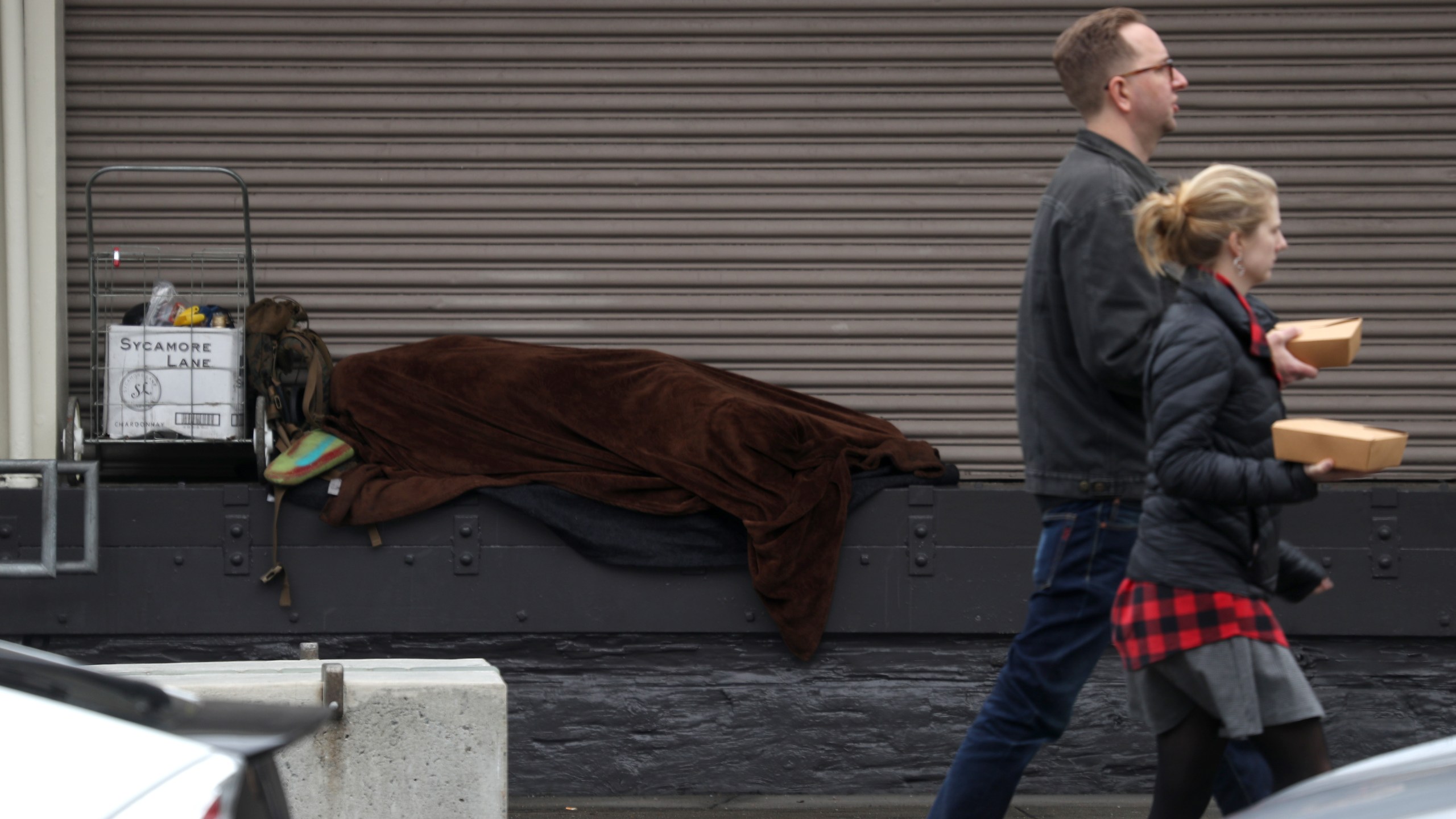 A homeless person sleeps on a loading dock in San Francisco on Dec. 5, 2019. (Credit: Justin Sullivan / Getty Images)