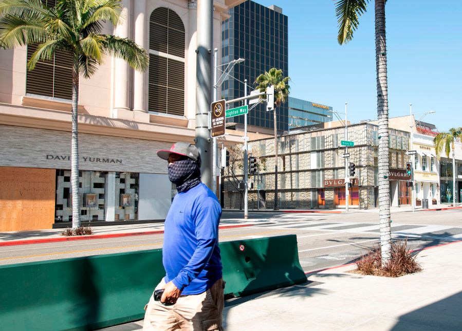 A person wearing a mask walks on Rodeo Drive in Beverly Hills on April 1, 2020, during the Covid 19 crisis. (VALERIE MACON/AFP via Getty Images)