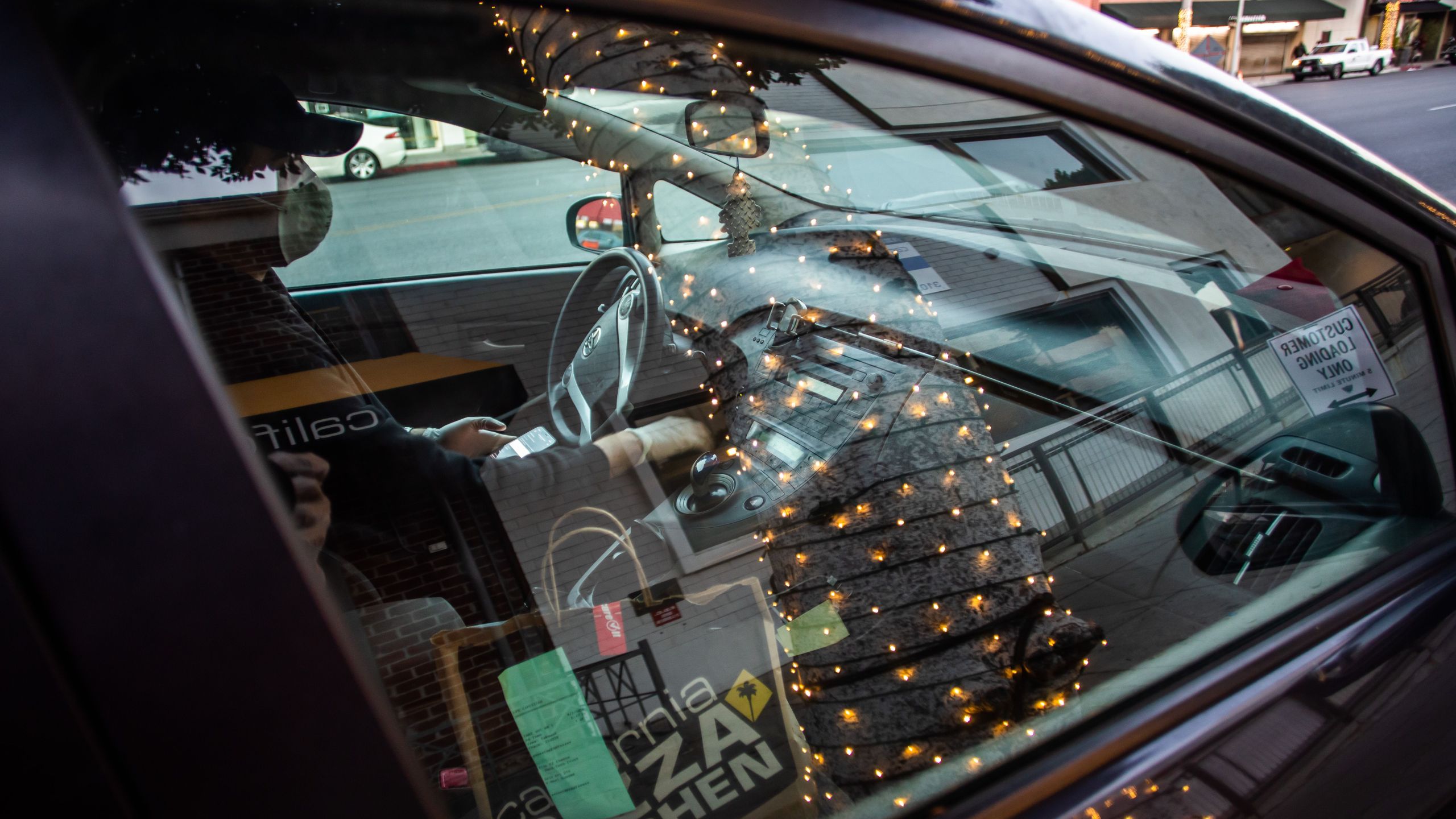 Musician Lucas Goes wears a mask as he drives to deliver food for a delivery app in Beverly Hills on April 2, 2020, after losing his job during the coronavirus outbreak. (Apu Gomes / AFP / Getty Images)