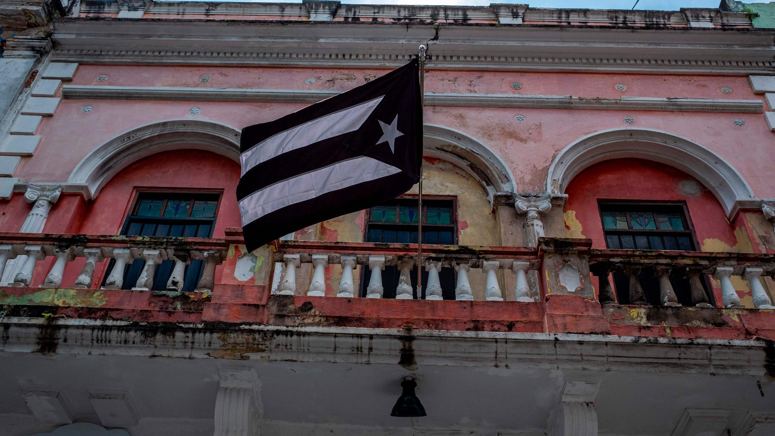 A black and white Puerto Rican National flag hangs from a balcony in Old San Juan, Puerto Rico on April 7, 2020. (RICARDO ARDUENGO/AFP via Getty Images)