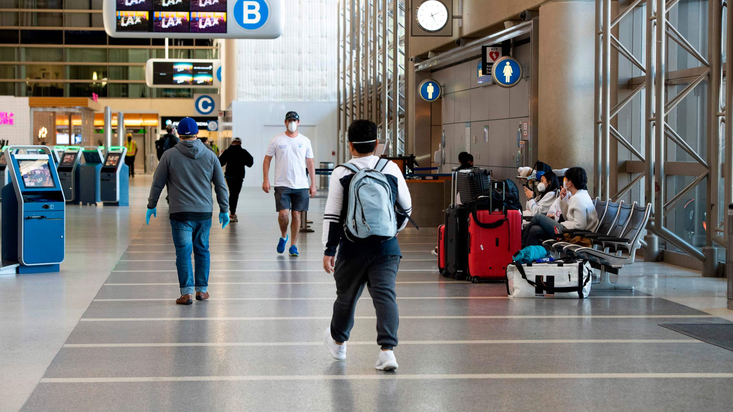 People wearing masks walk inside Tom Bradley Terminal at Los Angeles International Airport on April 16, 2020. (VALERIE MACON/AFP via Getty Images)