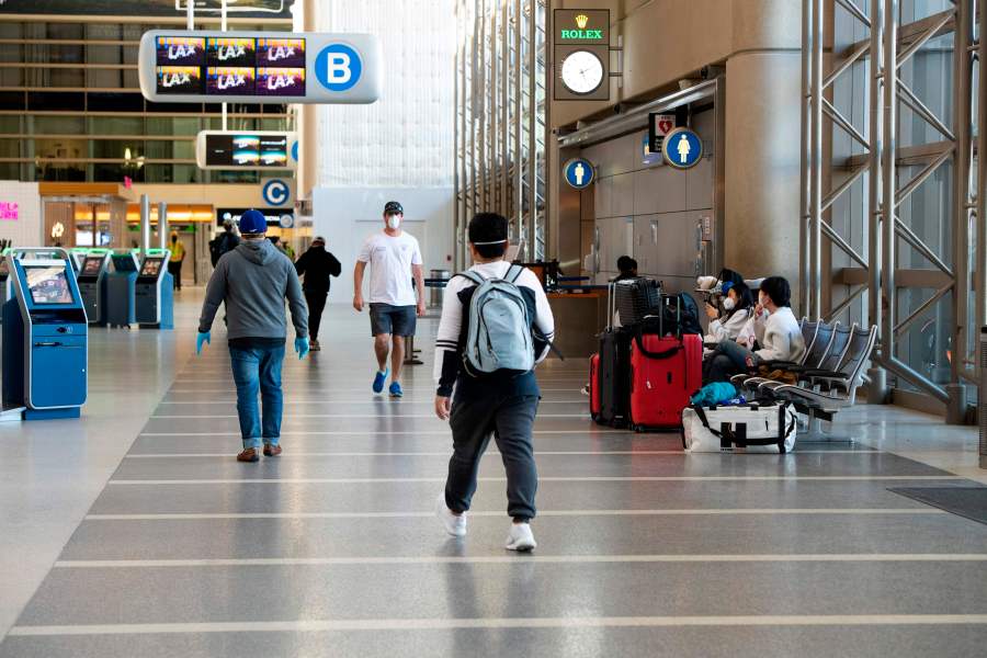 People wearing masks walk inside Tom Bradley Terminal at Los Angeles International Airport on April 16, 2020. (VALERIE MACON/AFP via Getty Images)