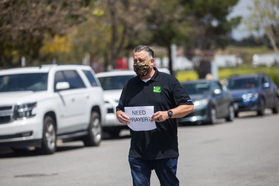 Simon Cooper offers prayers to people who attended an online Sunday Service inside their cars at the Christian '412 Church Murrieta' parking lot on April 19, 2020, in Murrieta, California. (APU GOMES/AFP via Getty Images)