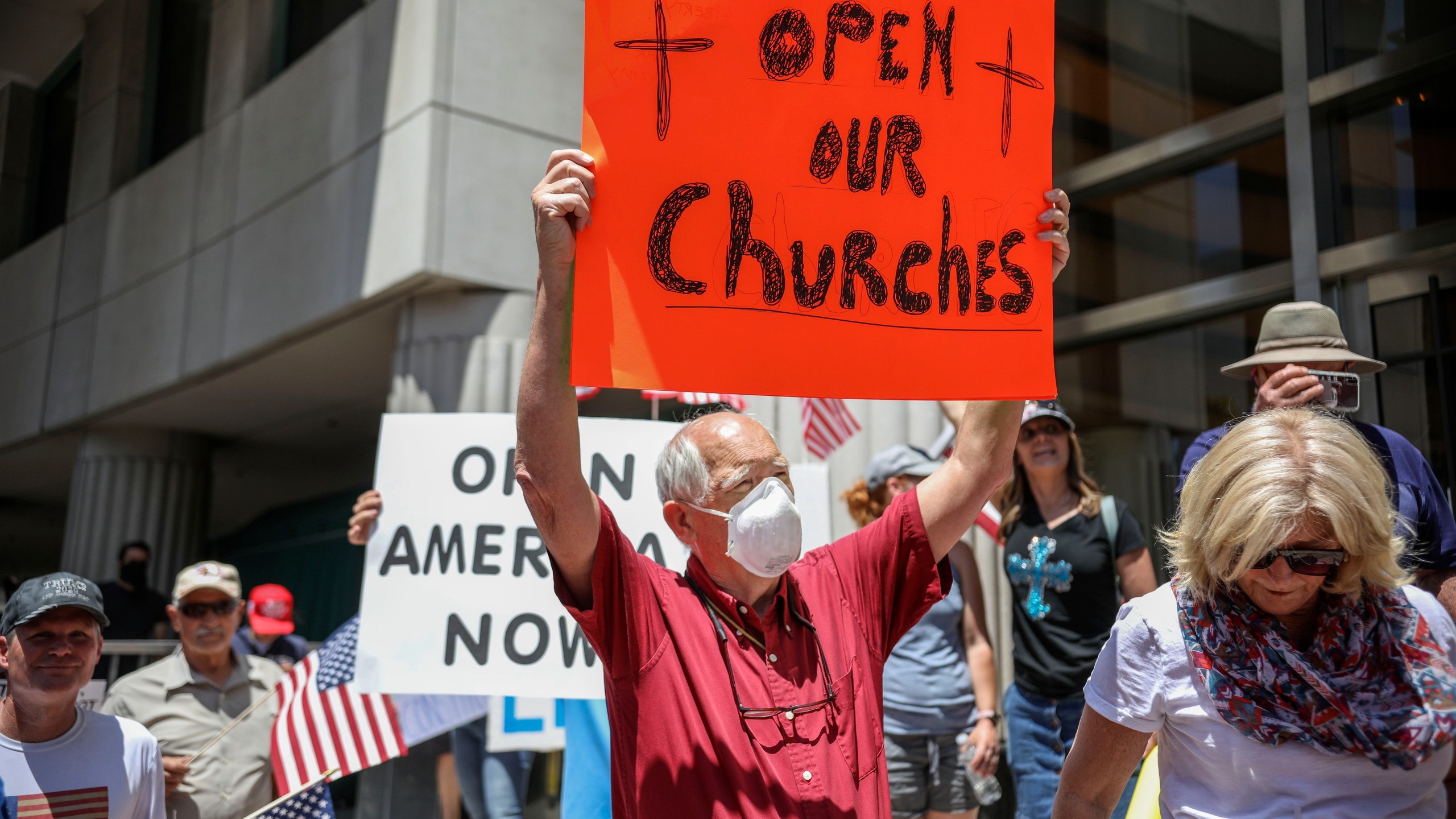 Demonstrators, holding signs demanding their church reopen, protest during a rally to reopen California and go against Stay-At-Home directives on May 1, 2020 in San Diego. Rallies have been held at several state capitols across the country as protesters express their deep frustration with the stay-at-home orders that are meant to stem the spread of the novel coronavirus. (Sandy Huffaker / AFP via Getty Images)