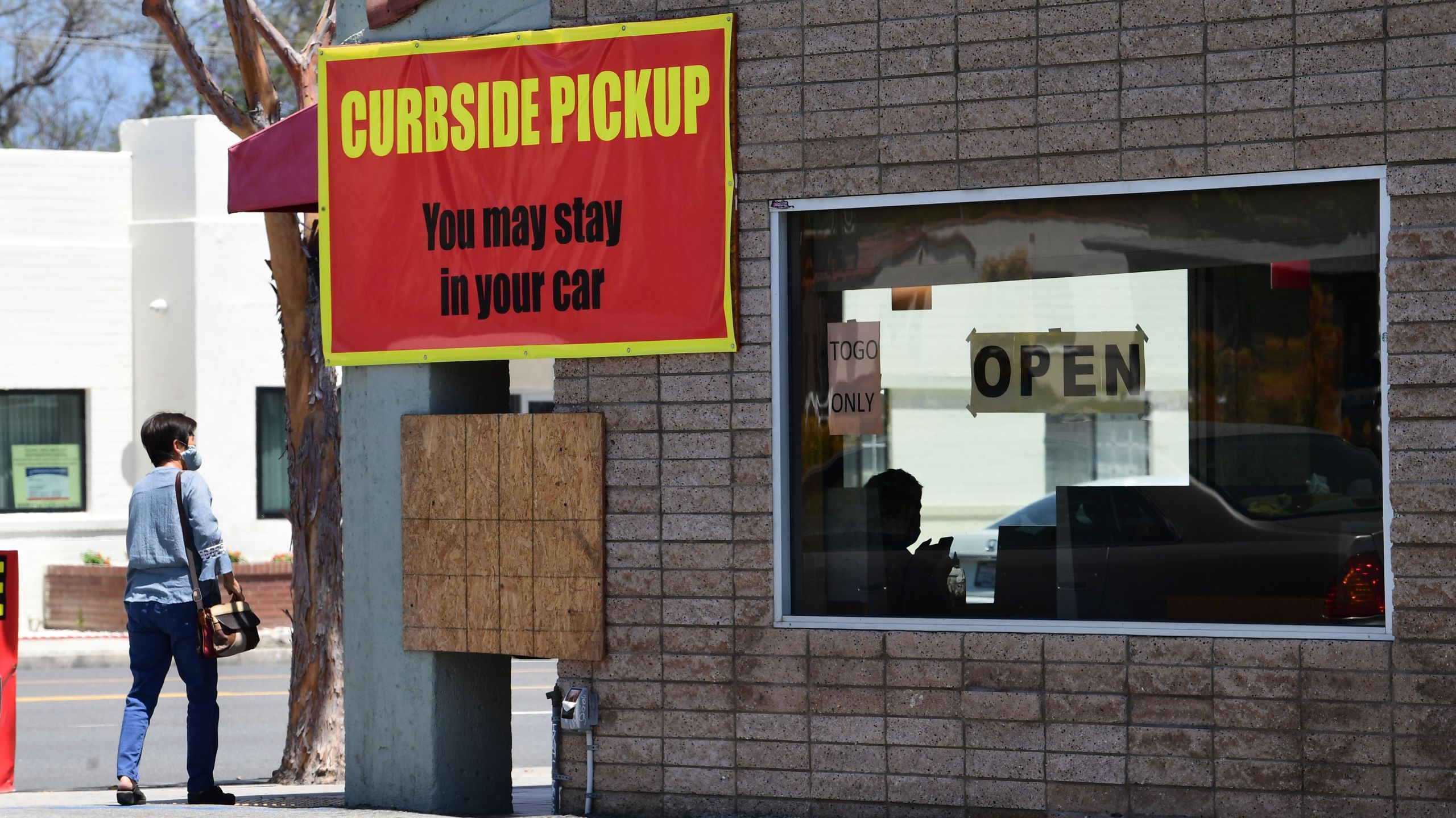 An employee inside a restaurant waits for customers arriving for pickup in Alhambra, California on May 7, 2020. (FREDERIC J. BROWN/AFP via Getty Images)