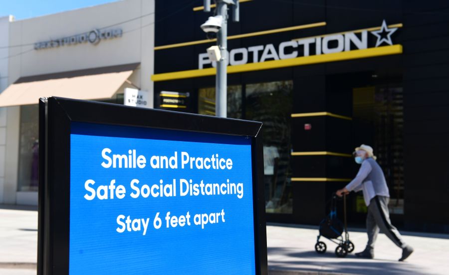 A sign reminds the public of social distancing rules but most businesses remain closed along the Third Street Promenade shopping street in Santa Monica on May 8, 2020. FREDERIC J. BROWN/AFP via Getty Images)