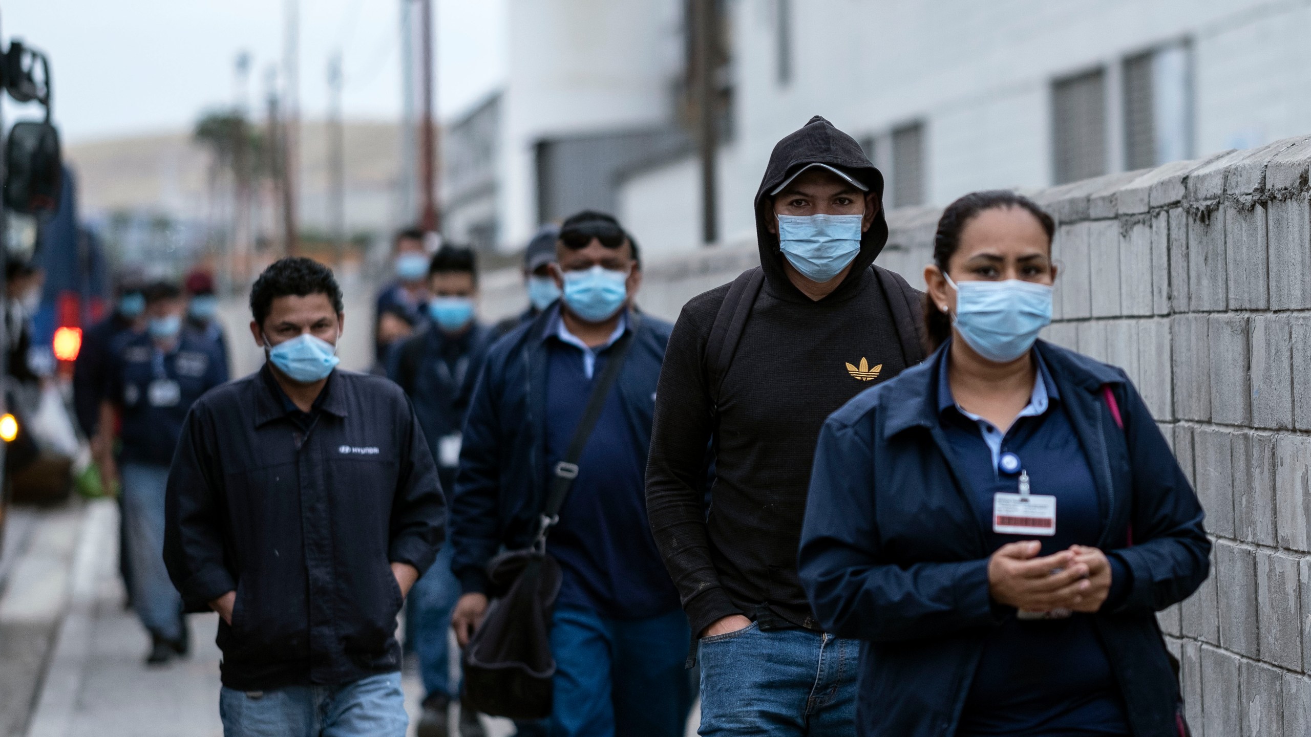 Production workers wearing face masks arrive for their shift at the Hyundai Plant in Tijuana, Baja California state, Mexico, on May 18, 2020, amid the COVID-19 pandemic. (GUILLERMO ARIAS/AFP via Getty Images)