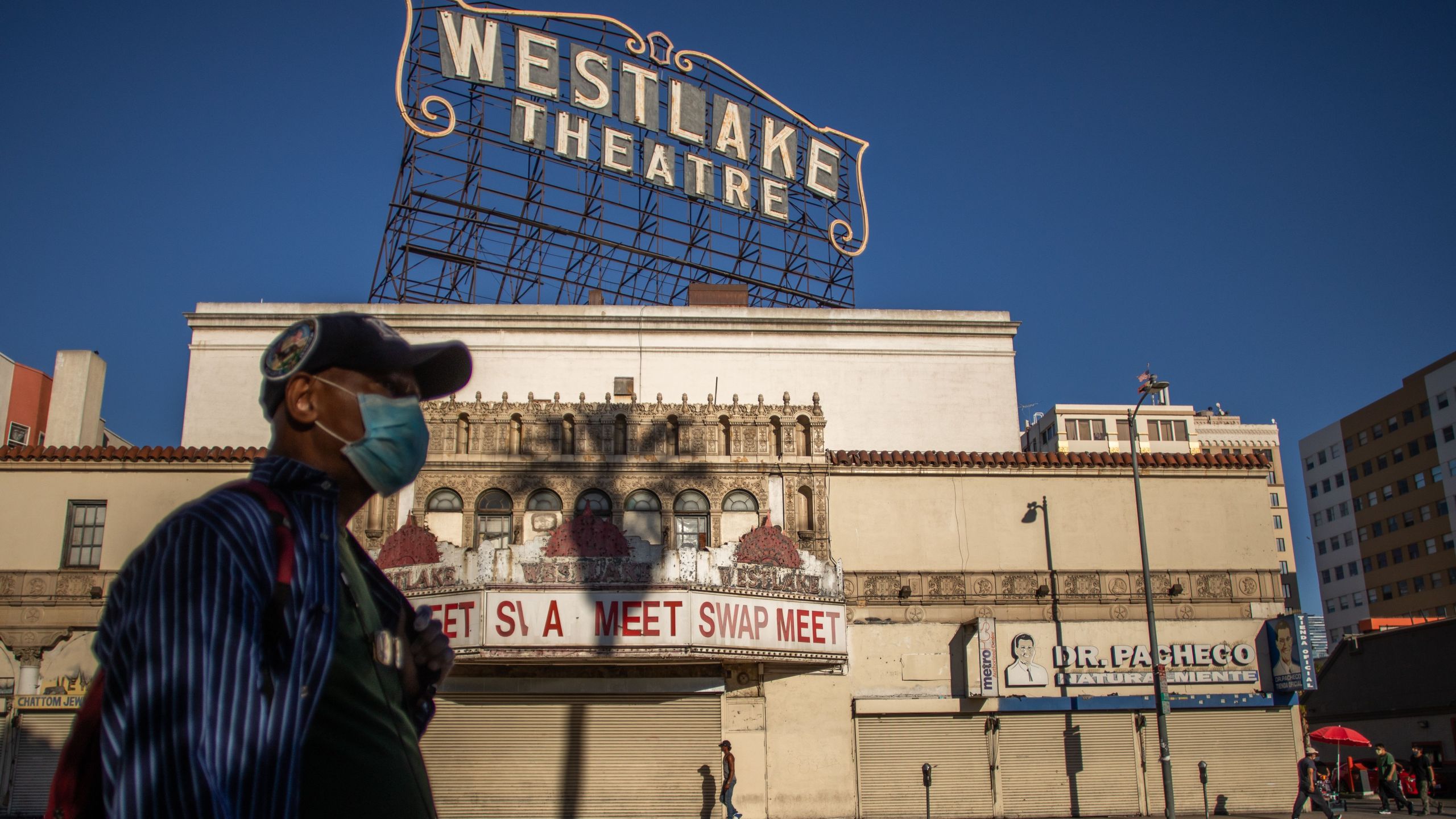 A man wearing a facemask walks in front of a closed store in the Westlake area by MacArthur Park, Los Angeles on May 21, 2020. (APU GOMES/AFP via Getty Images)