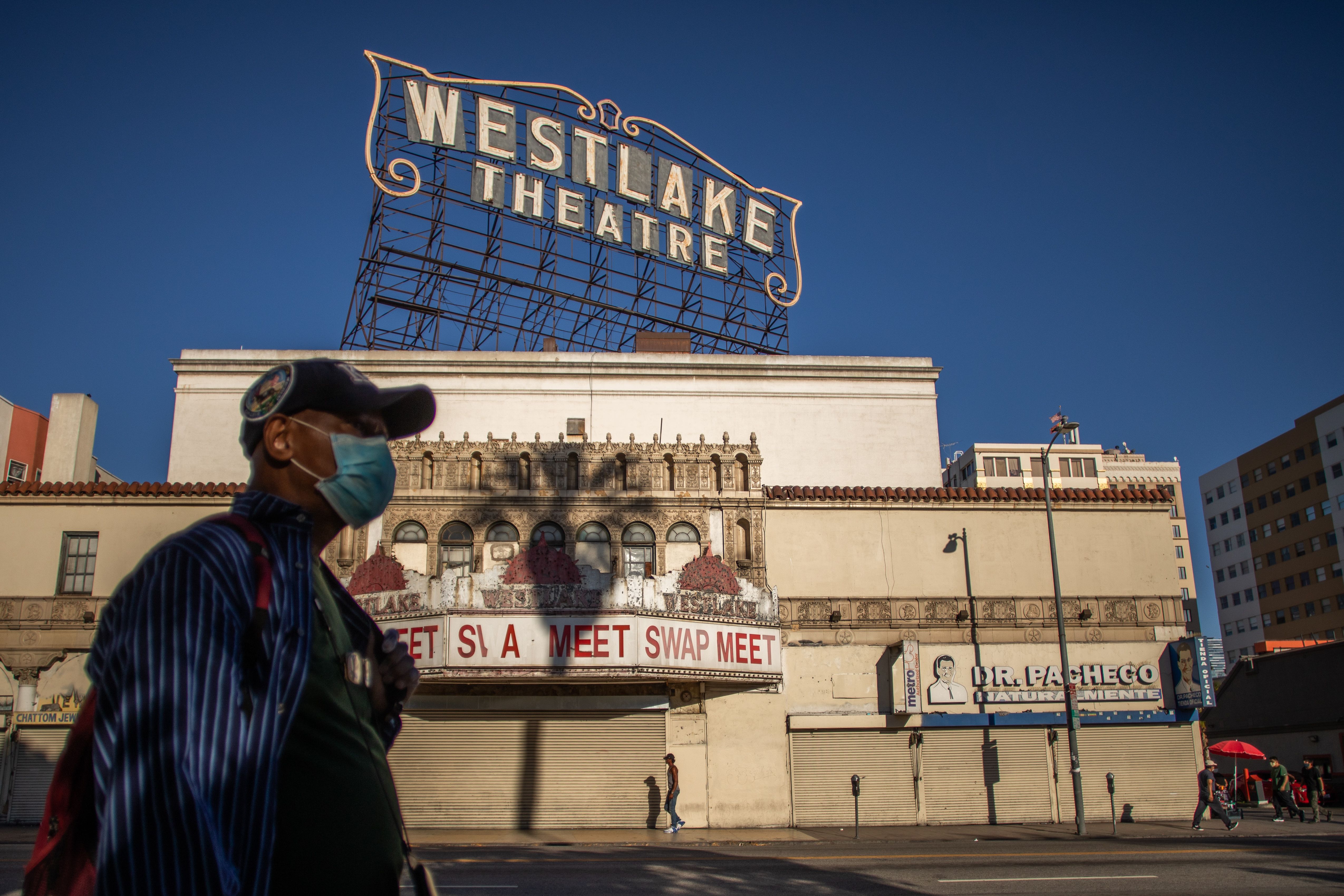 A man wearing a facemask walks in front of a closed store in the Westlake area by MacArthur Park, Los Angeles on May 21, 2020. (APU GOMES/AFP via Getty Images)