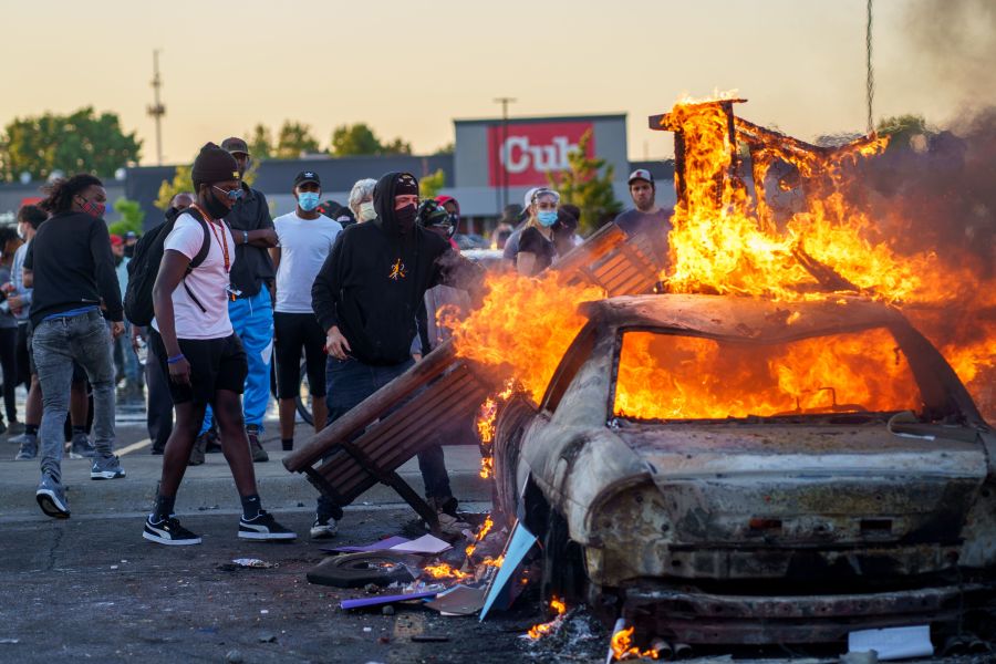 Protesters throw objects onto a burning car outside a Target store near the Third Police Precinct in Minneapolis, Minnesota, on May 28, 2020, during a demonstration over the death of George Floyd. (Kerem Yucel / AFP / Getty Images)